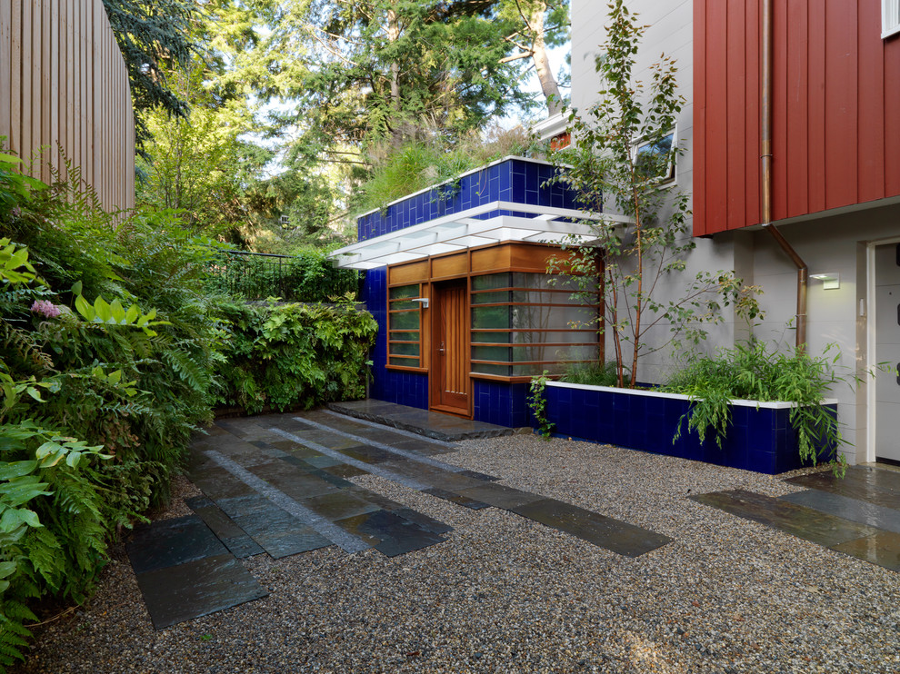 Modelo de acceso privado contemporáneo grande en patio con muro de contención, exposición parcial al sol y gravilla