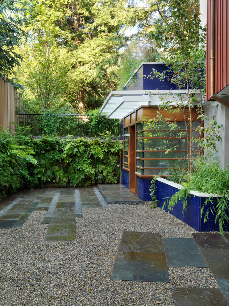 Exemple d'un grand jardin tendance avec un mur de soutènement, une exposition partiellement ombragée et du gravier.