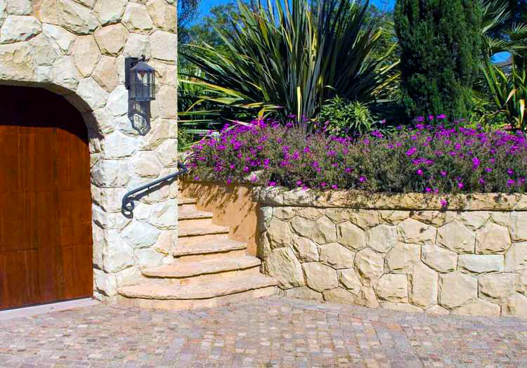 Foto di un vialetto d'ingresso tradizionale esposto in pieno sole di medie dimensioni e davanti casa in primavera con pavimentazioni in mattoni e un muro di contenimento