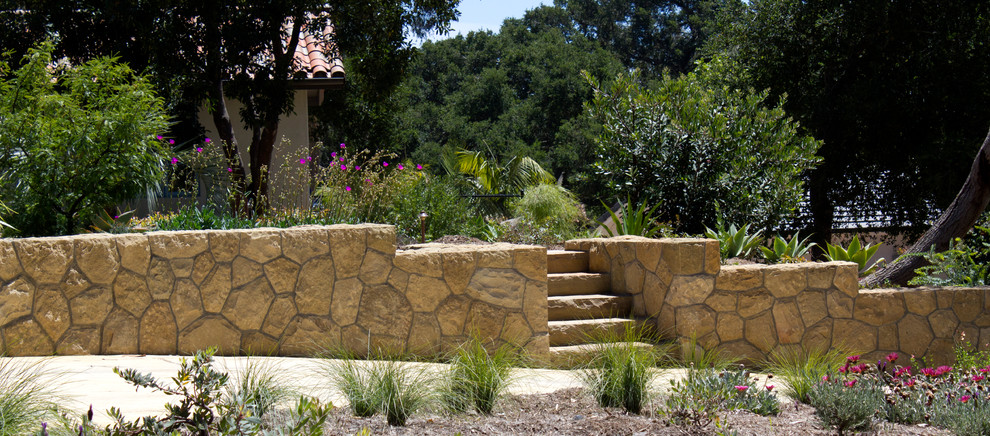 Aménagement d'un jardin avant méditerranéen de taille moyenne et l'été avec une exposition ensoleillée et des pavés en pierre naturelle.