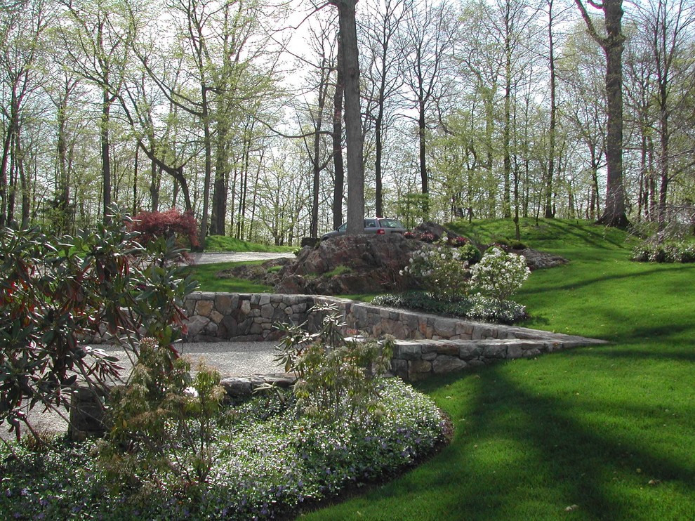 Foto di un giardino formale minimal esposto in pieno sole di medie dimensioni e dietro casa in primavera con un muro di contenimento e pavimentazioni in pietra naturale