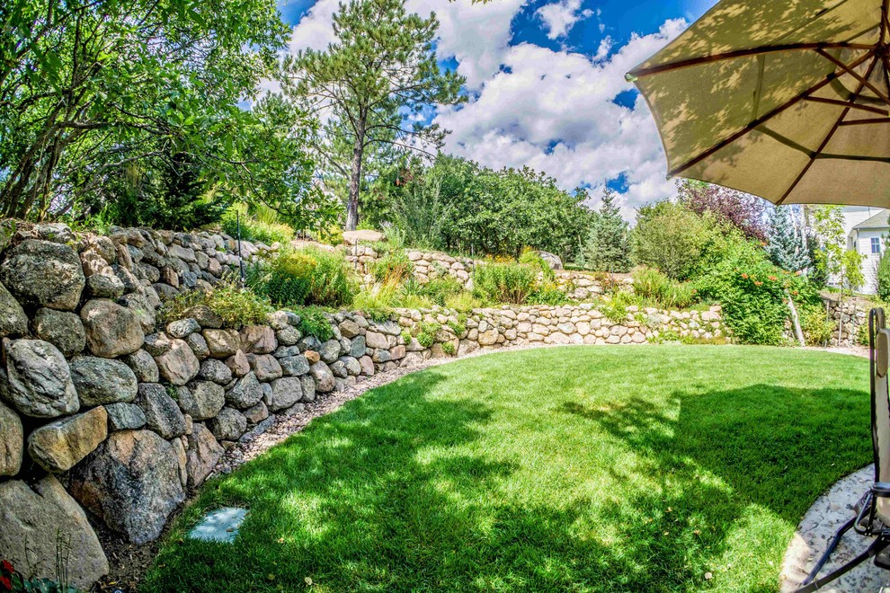 Immagine di un giardino xeriscape tradizionale esposto a mezz'ombra di medie dimensioni e dietro casa in estate con un muro di contenimento e pavimentazioni in pietra naturale