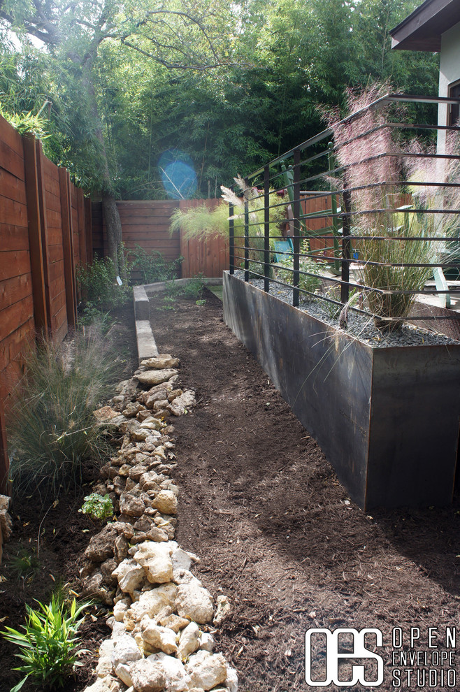 Immagine di un piccolo giardino moderno esposto a mezz'ombra dietro casa con un muro di contenimento e pedane