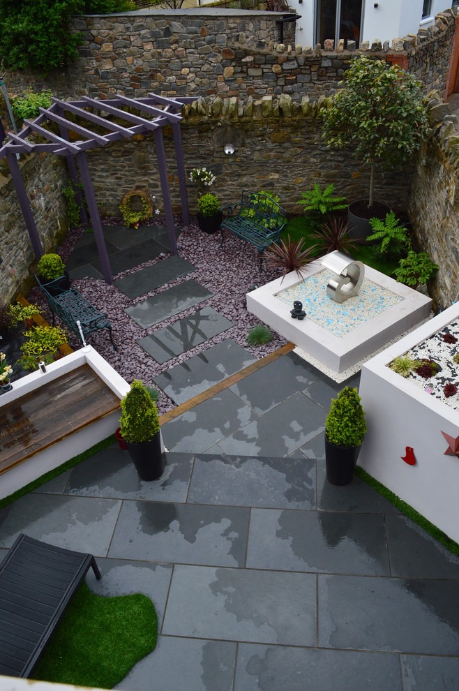 Kleiner Moderner Garten hinter dem Haus mit Kübelpflanzen und Natursteinplatten in Cardiff