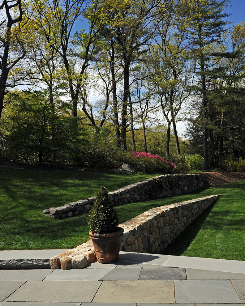 Ispirazione per un grande giardino formale design dietro casa con un muro di contenimento e pavimentazioni in pietra naturale