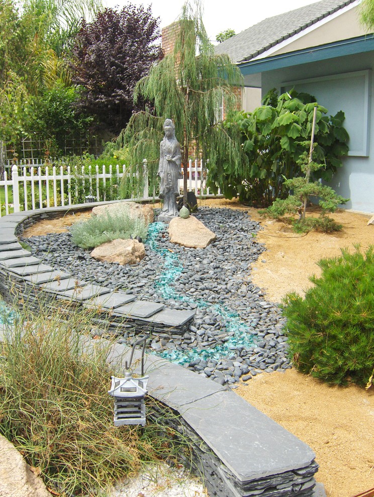 This is an example of a medium sized bohemian front full sun garden in Los Angeles with gravel.