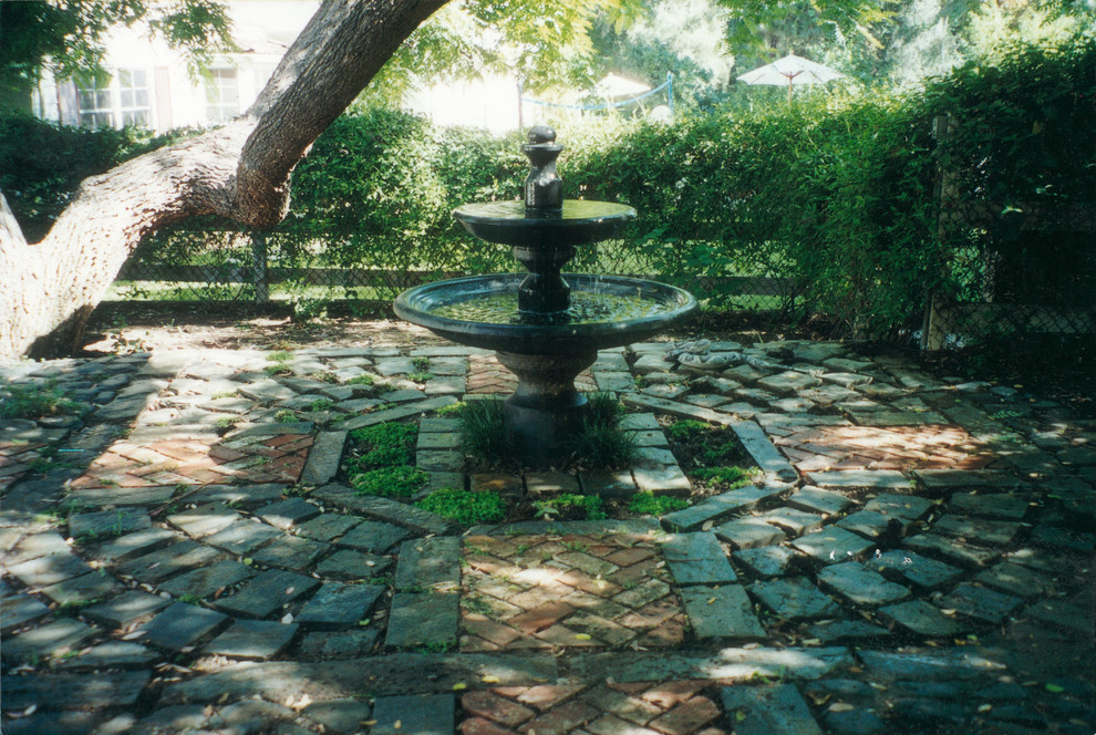 Diseño de jardín clásico de tamaño medio en primavera en patio trasero con exposición parcial al sol, adoquines de ladrillo y fuente