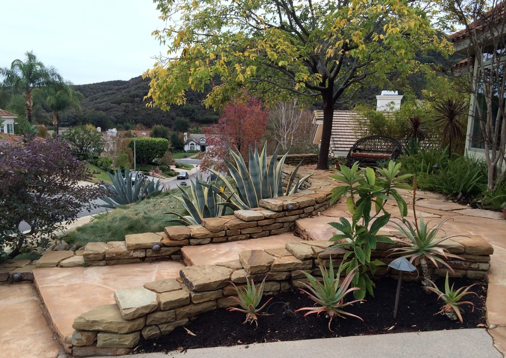 Ejemplo de jardín de secano mediterráneo grande en verano en patio delantero con exposición total al sol, adoquines de piedra natural y fuente