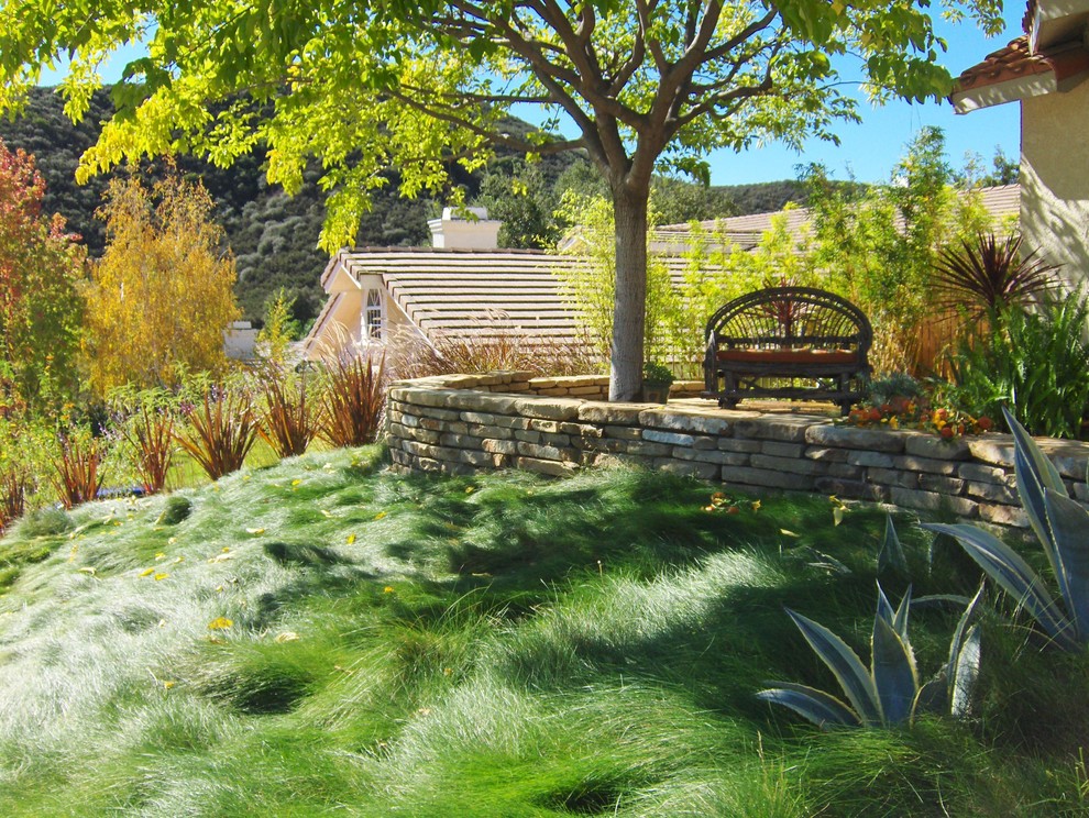 Esempio di un giardino formale rustico in ombra di medie dimensioni e dietro casa in primavera con un muro di contenimento e pavimentazioni in pietra naturale