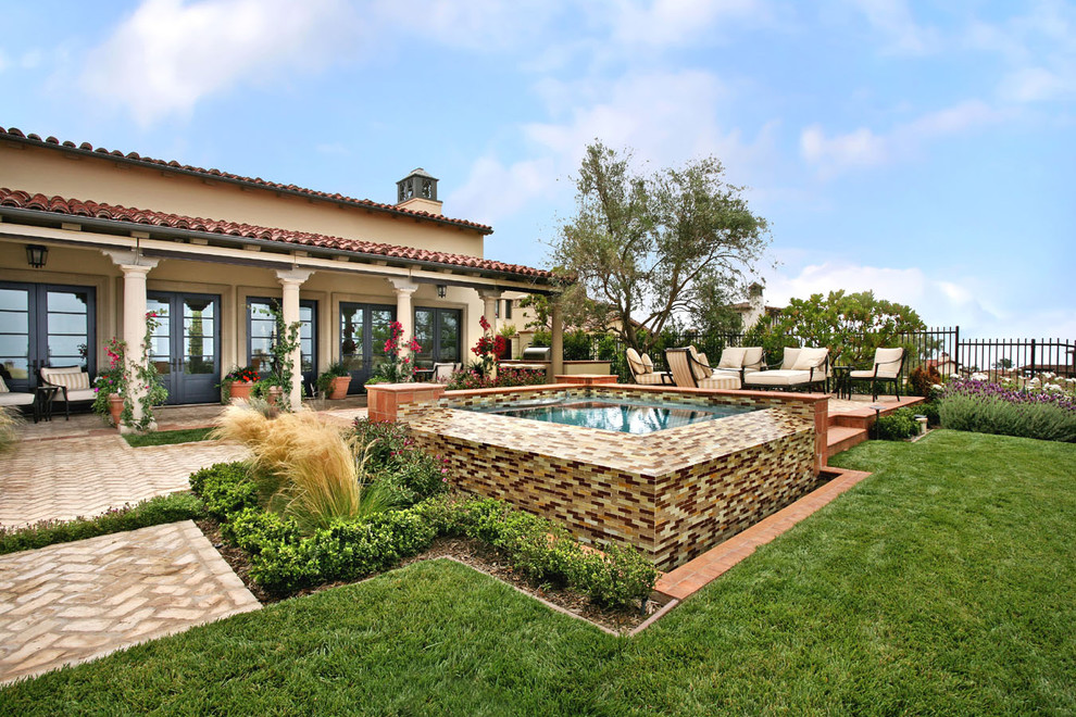 Mediterranean back garden in Los Angeles with a water feature and brick paving.