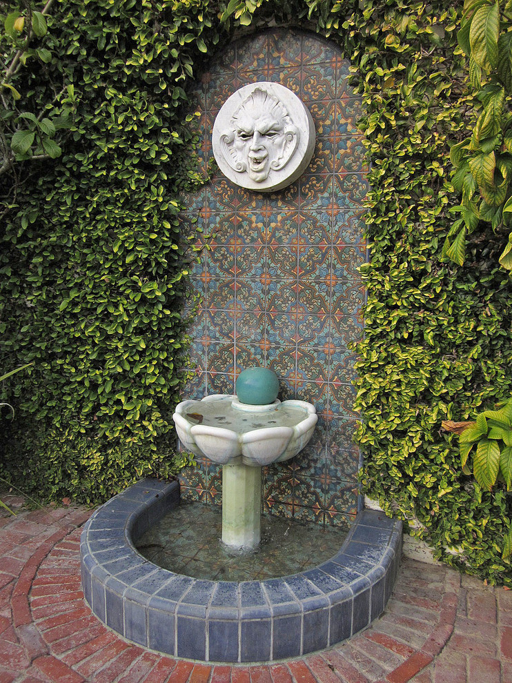 На фото: большой садовый фонтан на заднем дворе в средиземноморском стиле с мощением клинкерной брусчаткой
