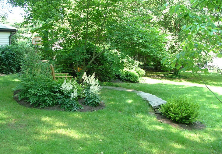 Small rustic back partial sun garden in New York with a retaining wall.