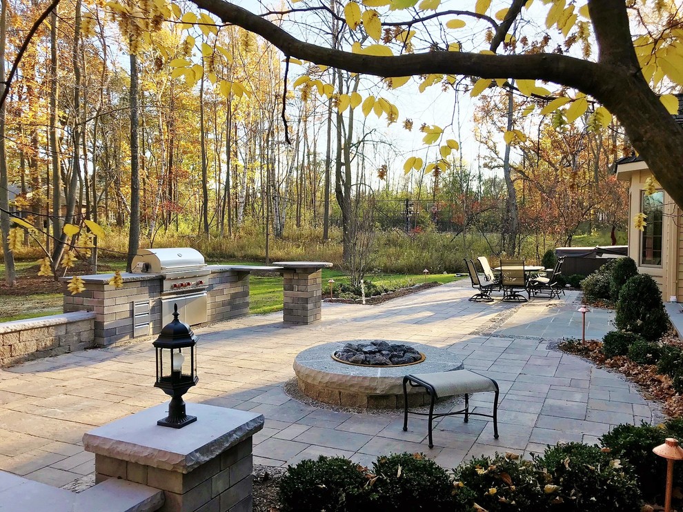 Modelo de jardín tradicional grande en patio trasero con brasero, exposición parcial al sol y adoquines de hormigón