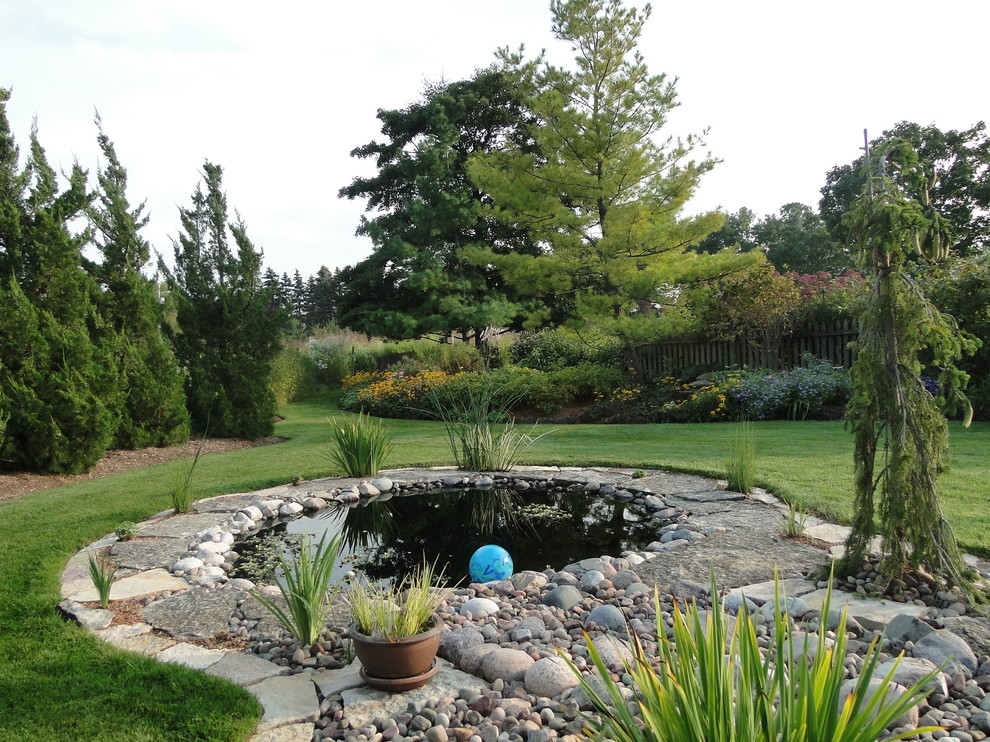 Medium sized rural back formal full sun garden for summer in Milwaukee with a pond and natural stone paving.