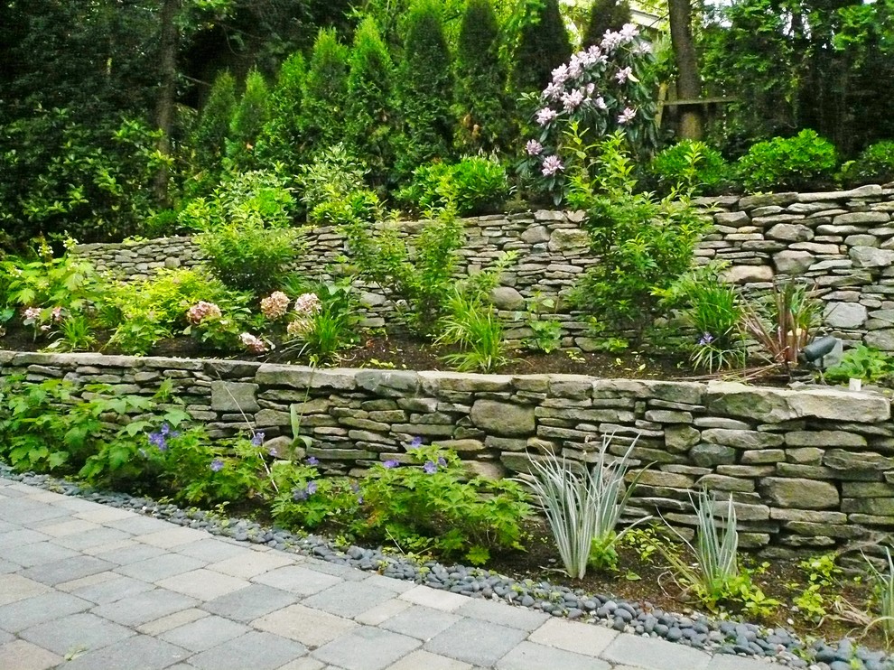 Ispirazione per un grande giardino xeriscape esposto a mezz'ombra con un muro di contenimento, un pendio, una collina o una riva e pavimentazioni in cemento