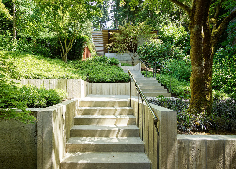 На фото: участок и сад на переднем дворе в современном стиле с подпорной стенкой и мощением тротуарной плиткой