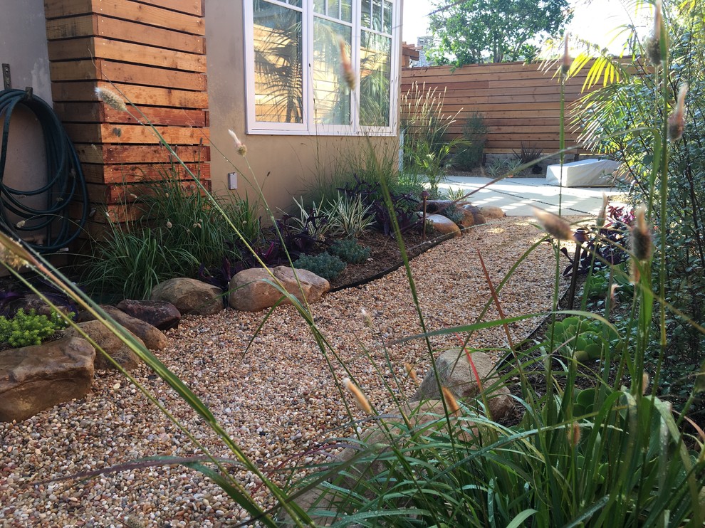 Modelo de jardín exótico de tamaño medio en patio lateral con exposición parcial al sol y gravilla