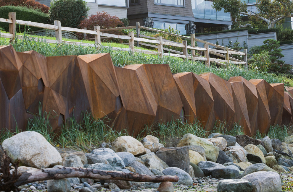 Photo of a large contemporary full sun hillside retaining wall landscape in Vancouver.