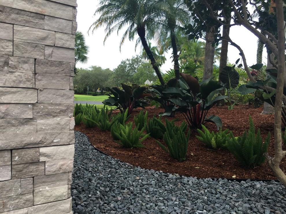 Large mediterranean front formal full sun garden in Miami with a garden path and mulch.