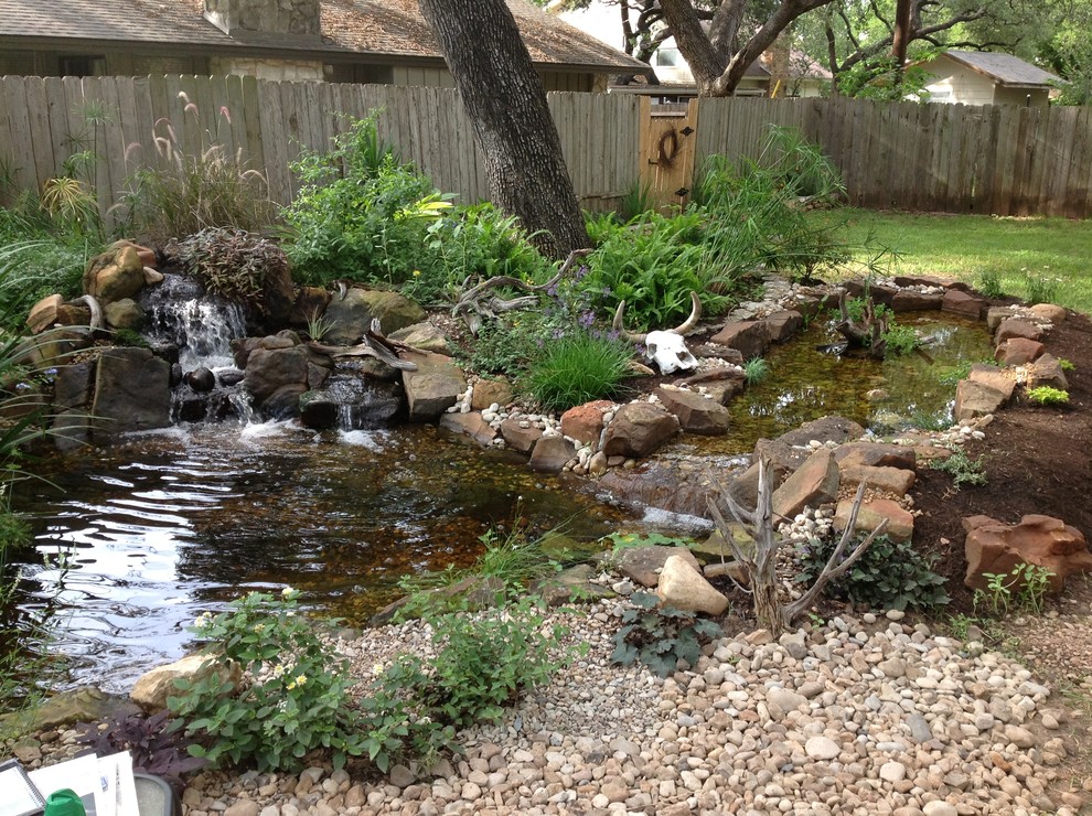 This is an example of a mid-sized traditional shade backyard gravel water fountain landscape in Austin.