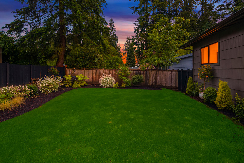 This is an example of a large back xeriscape full sun garden for spring in Seattle with concrete paving.