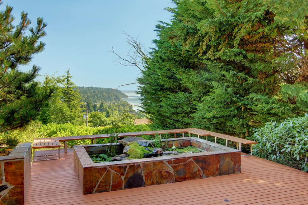 This is an example of a mid-century modern backyard water fountain landscape in Seattle with decking.