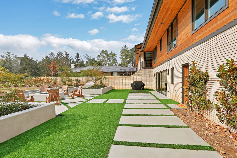 This is an example of a large mid-century modern full sun backyard concrete paver landscaping in Other with a fire pit.