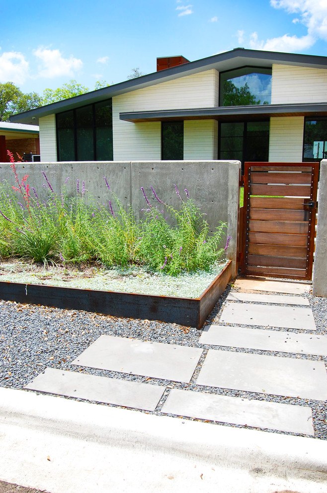 Photo of a medium sized retro front xeriscape full sun garden in Austin with a potted garden and concrete paving.