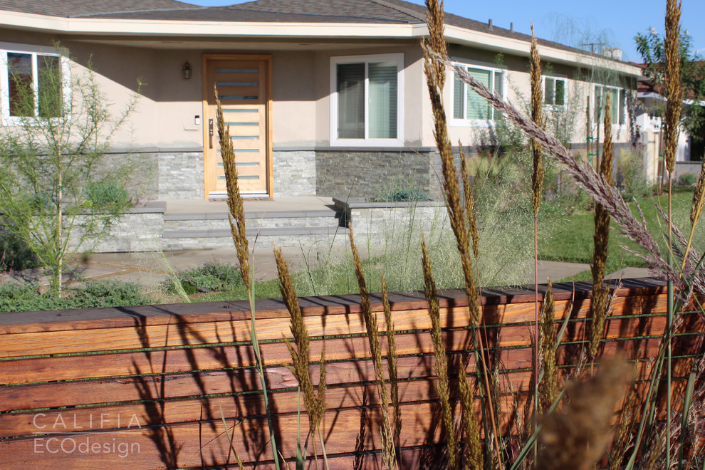 Exempel på en mellanstor 50 tals trädgård i full sol framför huset på hösten, med marksten i betong