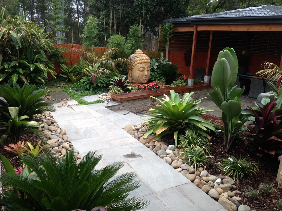 Esempio di un giardino tropicale dietro casa e di medie dimensioni con fontane e pavimentazioni in pietra naturale