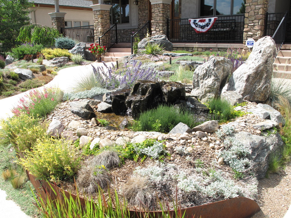 This is an example of a mid-sized southwestern drought-tolerant and full sun front yard concrete paver water fountain landscape in Denver for summer.