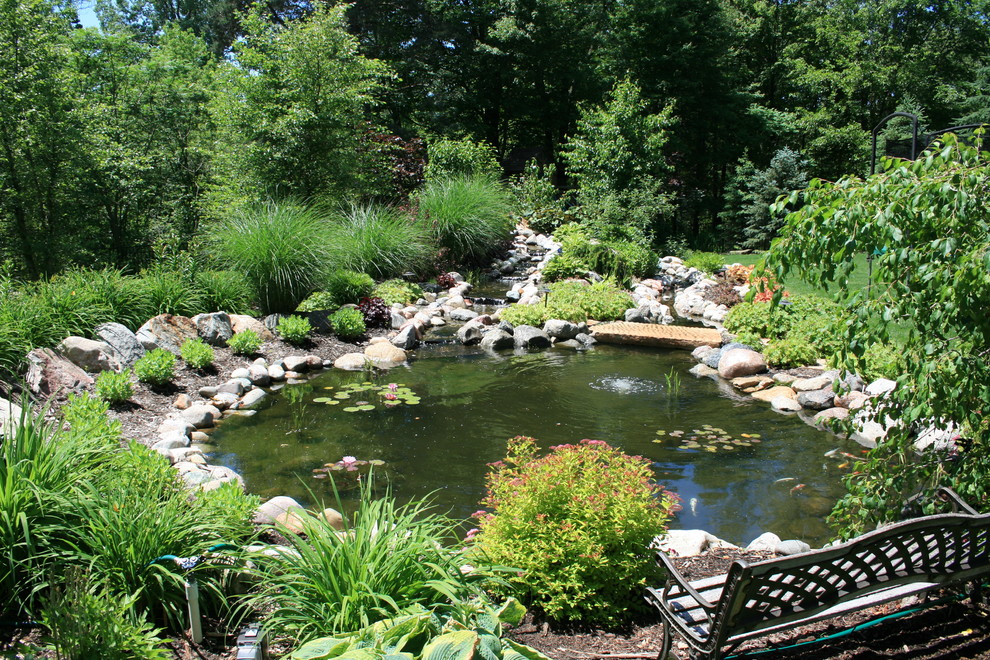 Foto di un grande laghetto da giardino tradizionale esposto in pieno sole dietro casa con pacciame