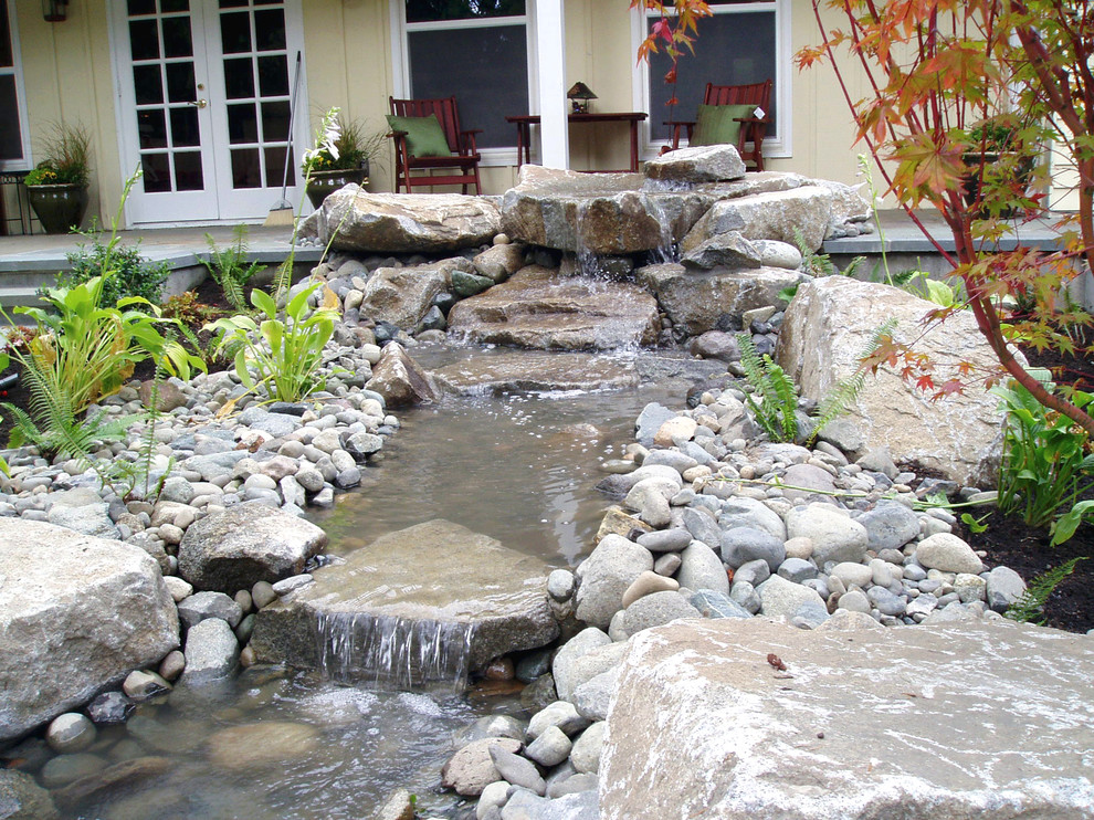 This is an example of a mid-sized traditional partial sun backyard stone landscaping in Seattle for spring.