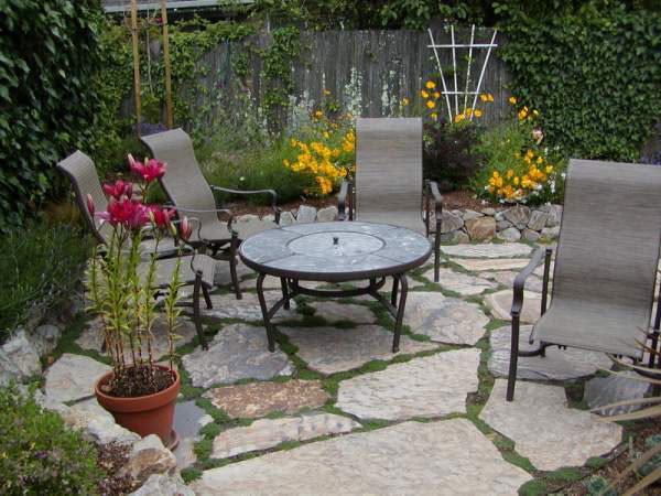 Cette image montre un petit jardin latéral méditerranéen au printemps avec un mur de soutènement, une exposition partiellement ombragée et des pavés en pierre naturelle.