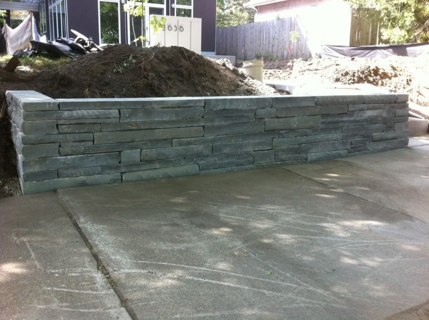 This is an example of a medium sized modern front garden in Minneapolis with a retaining wall and natural stone paving.
