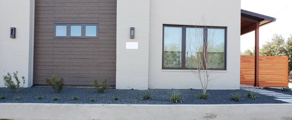 Immagine di un giardino xeriscape minimalista esposto a mezz'ombra di medie dimensioni e davanti casa con ghiaia
