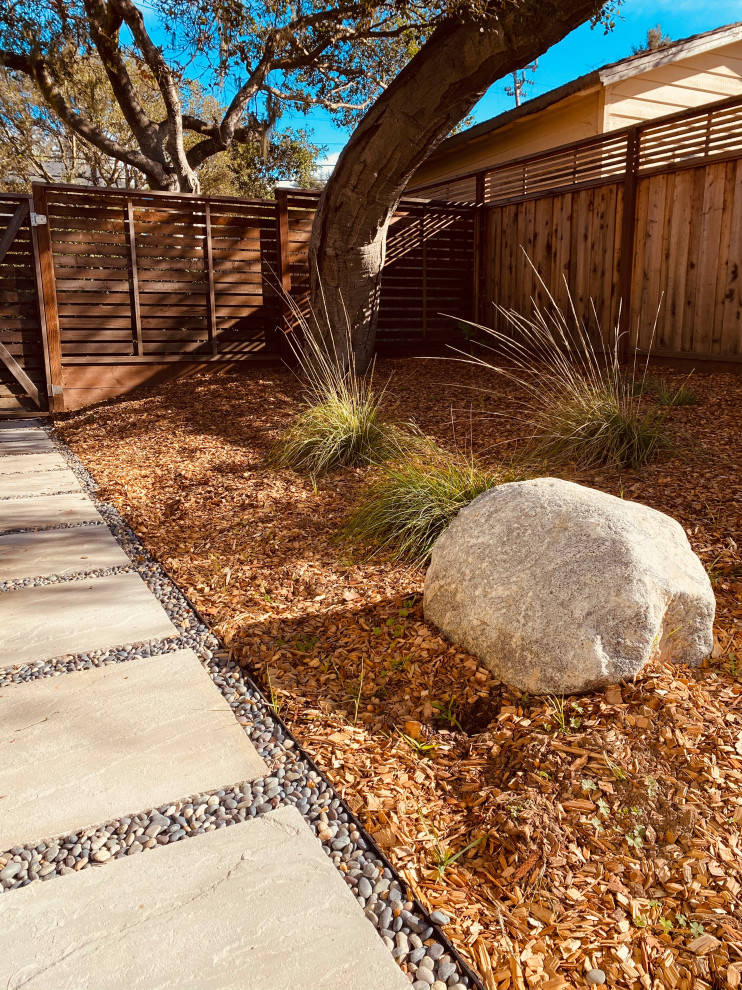 Foto di un giardino minimalista esposto a mezz'ombra di medie dimensioni e nel cortile laterale con pavimentazioni in pietra naturale e recinzione in legno