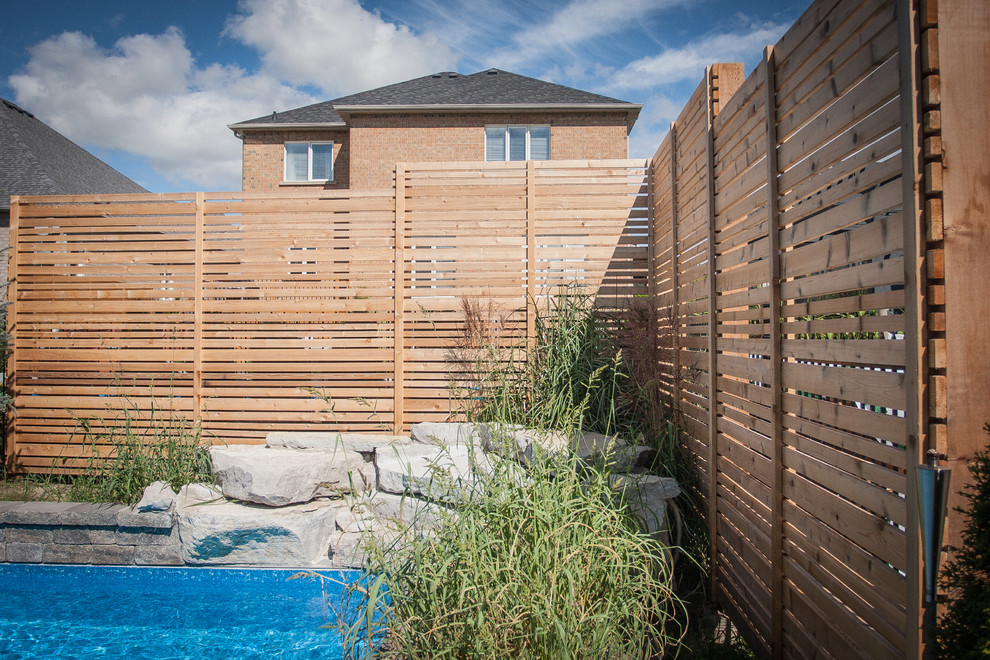Foto di un giardino formale moderno esposto in pieno sole di medie dimensioni e dietro casa in estate con un muro di contenimento e pavimentazioni in pietra naturale