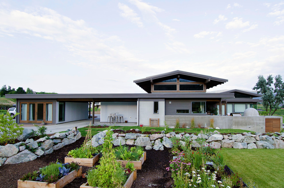 Diseño de jardín moderno grande en patio trasero con muro de contención, exposición parcial al sol y mantillo