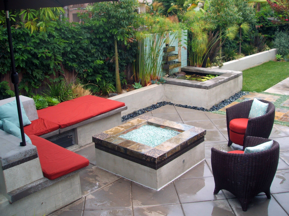 This is an example of a medium sized modern back patio in San Diego with a water feature and decking.
