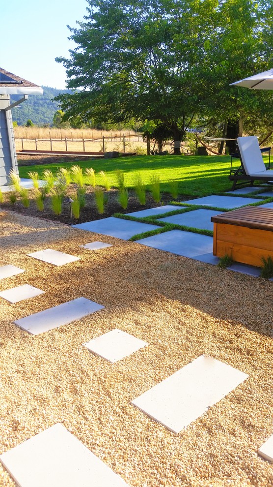 Lantlig inredning av en liten trädgård i full sol, med en trädgårdsgång och marksten i betong på sommaren