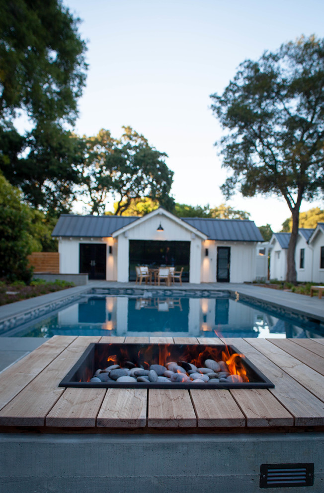 Large rural back full sun garden in San Francisco with a fire feature and natural stone paving.