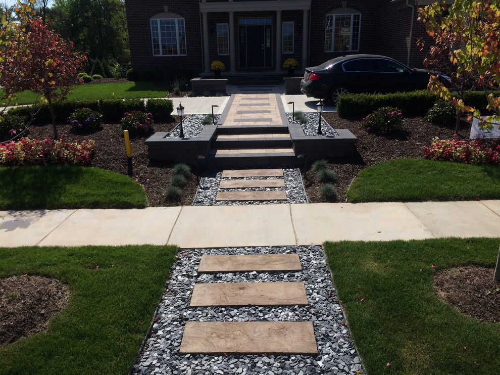 This is an example of a medium sized modern front formal full sun garden in Detroit with a retaining wall and brick paving.