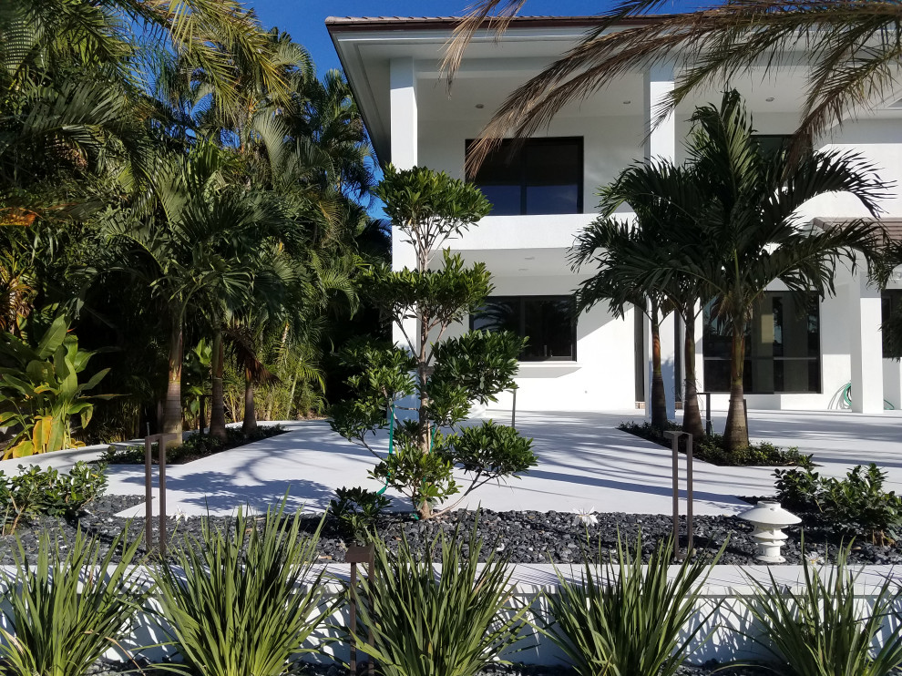 На фото: большой участок и сад на переднем дворе в стиле модернизм с подъездной дорогой и покрытием из каменной брусчатки