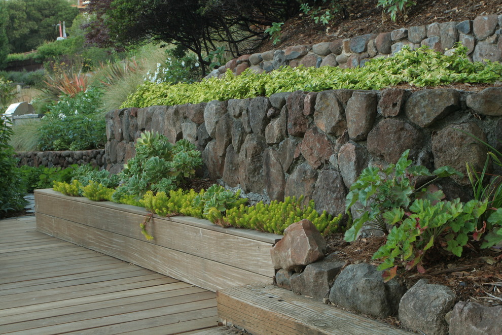 Inspiration pour un jardin minimaliste avec une pente, une colline ou un talus et une terrasse en bois.