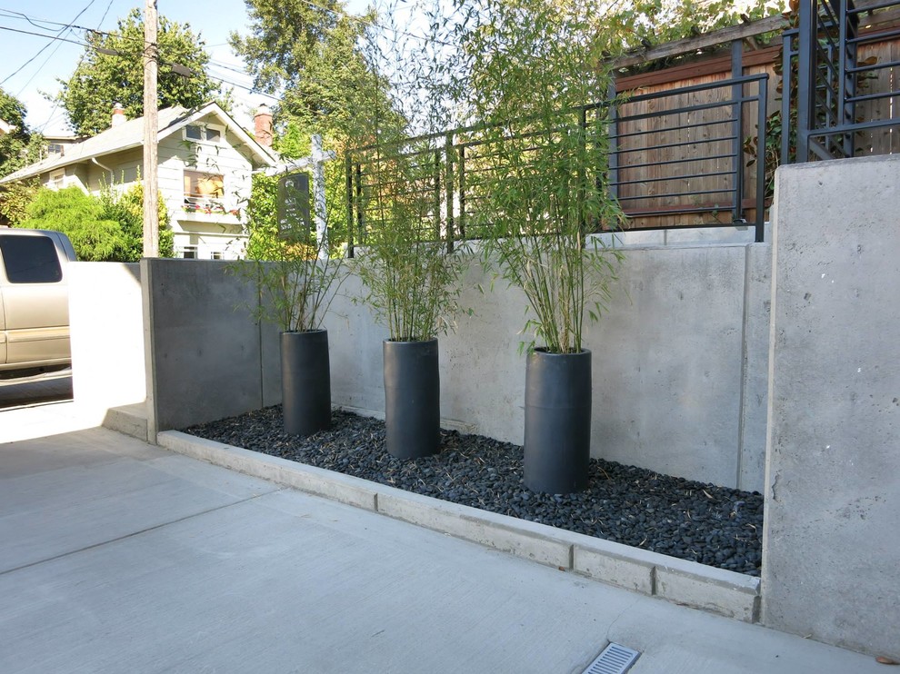 This is an example of a mid-sized modern shade front yard concrete paver driveway in Seattle.