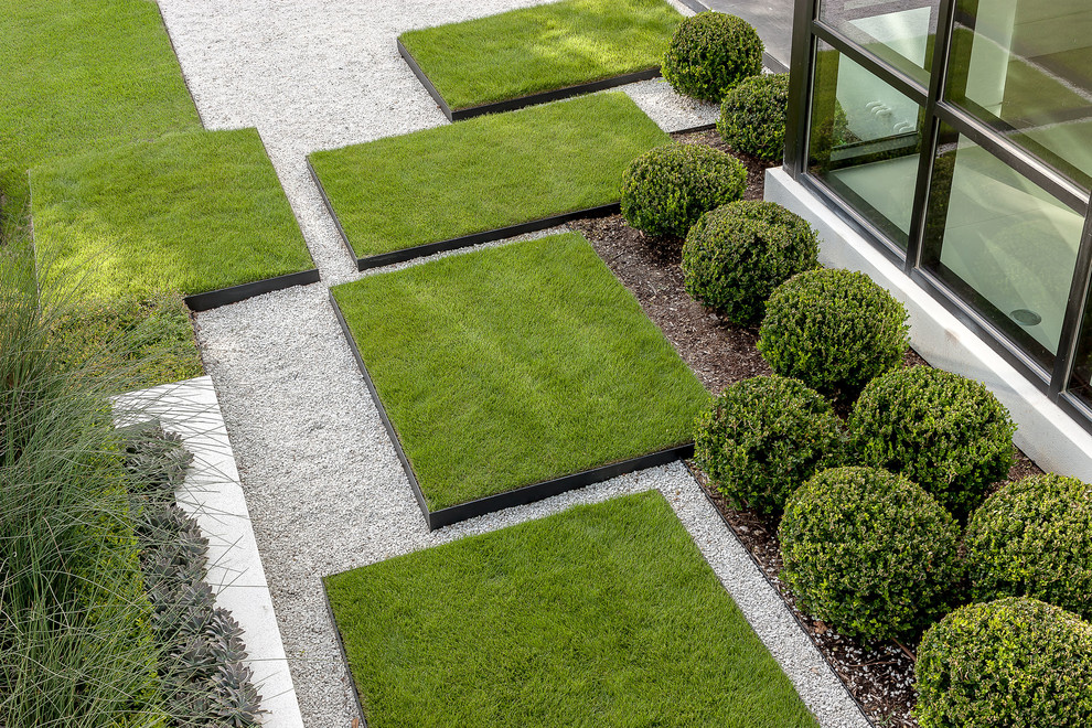 Modelo de jardín minimalista extra grande en patio delantero con exposición total al sol, gravilla y borde del césped
