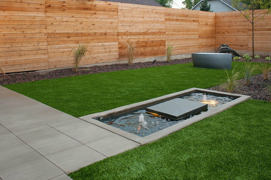Kleiner Moderner Garten hinter dem Haus mit Wasserspiel, direkter Sonneneinstrahlung und Betonboden in Denver