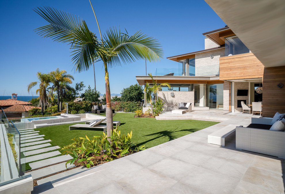 Expansive beach style back full sun garden for summer in Los Angeles with a garden path and concrete paving.