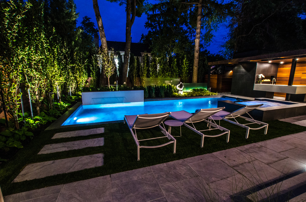 Diseño de piscina con fuente actual pequeña en patio trasero con adoquines de piedra natural